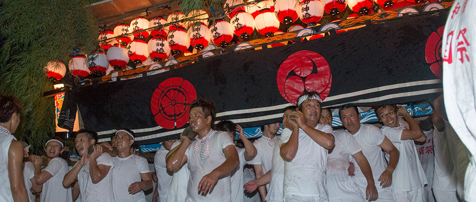 古和浦の祇園祭を写した写真。多数の提灯が吊り下げられた神輿を多数の男性が担いでいる。