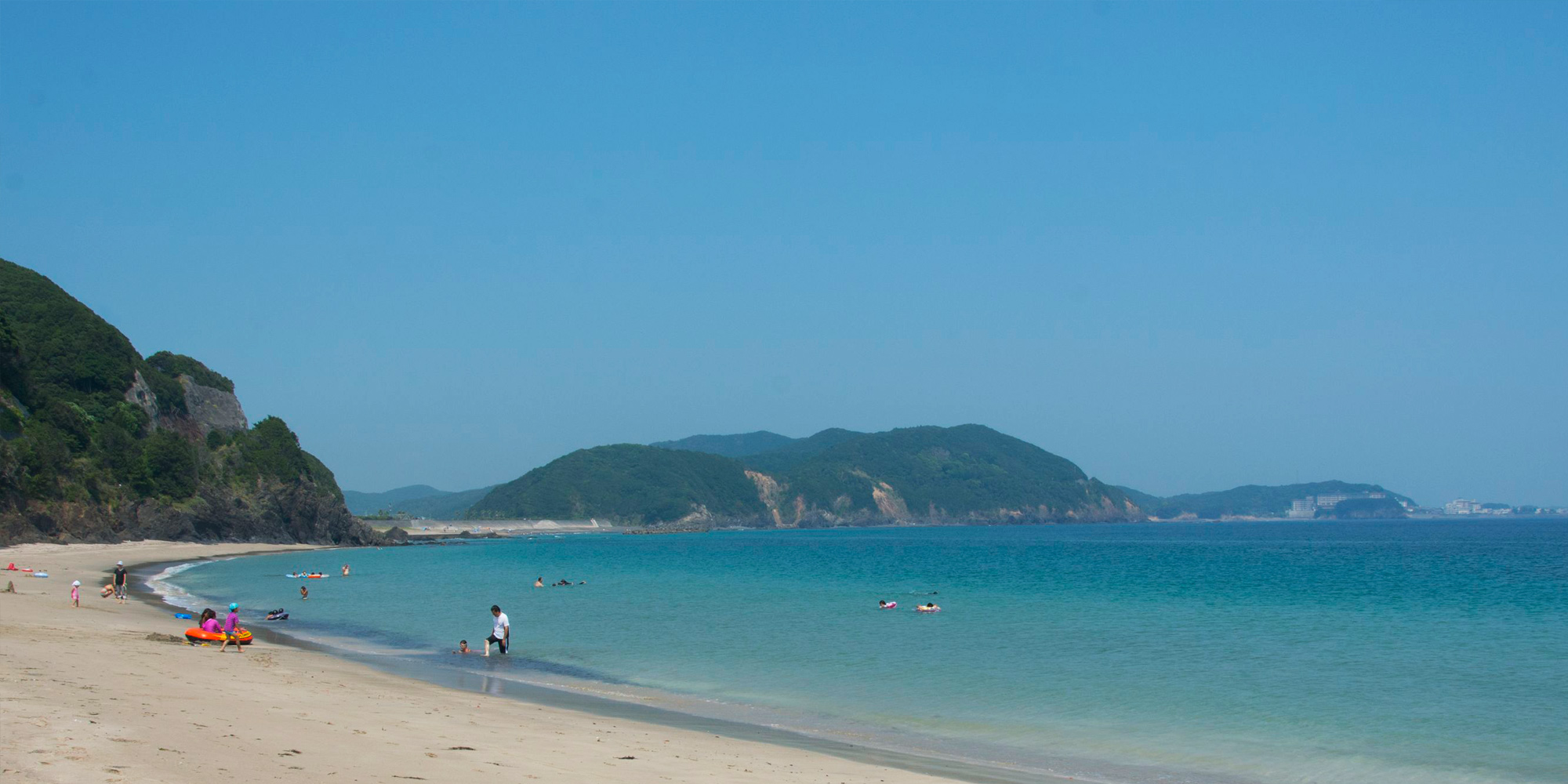 田曽白浜を写した写真。海水浴を楽しむ人々が写っている。