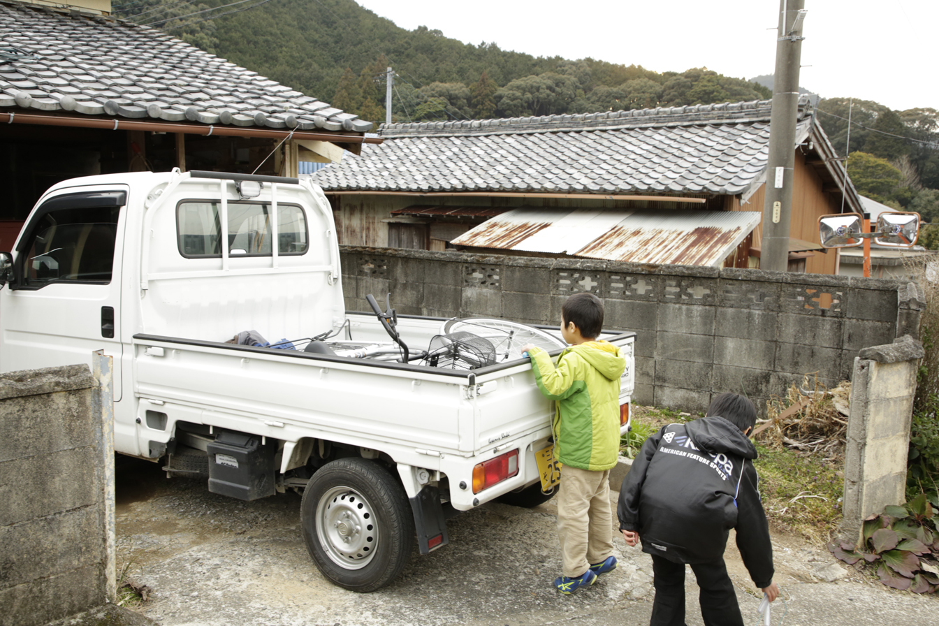 谷川原さんの軽トラックの荷台を覗いている子供たちの写真。